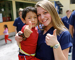 Medical volunteer and young child with thumbs up 